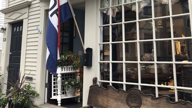 A two-story building with a flag, a bench, and a window with curtains. - Spacious home in the Heart of Downtown Newport! Walk Everywhere  (Newport)