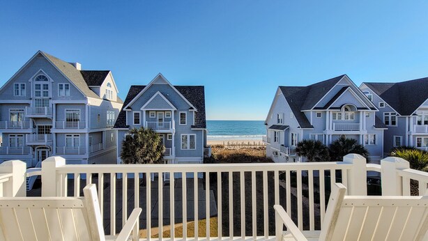 Una propiedad frente al mar con varias casas, una terraza de madera y vista al océano.