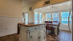 Una cocina con una isla grande, un comedor con vistas y un reloj en la pared.