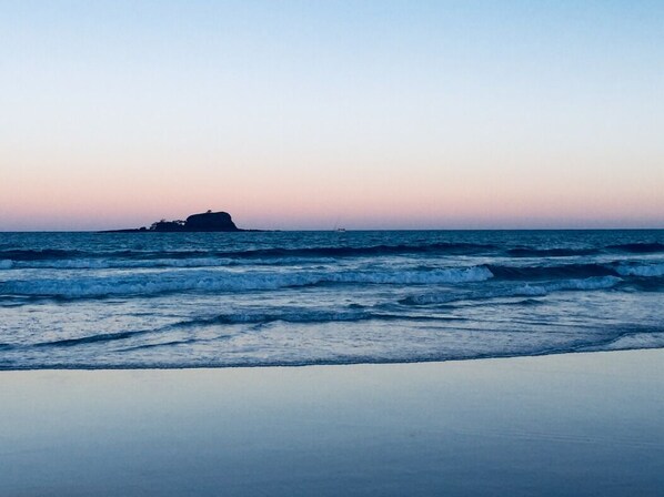 Ein Strand mit Wellen und einer fernen Insel.