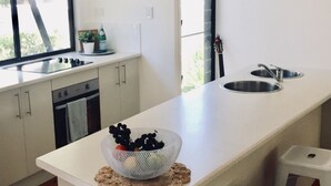 Une cuisine moderne dotée d’un îlot central, d’un évier et d’une fenêtre laissant entrer la lumière naturelle.