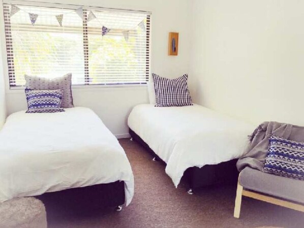 A room with two beds, a sofa, and a window with blinds.