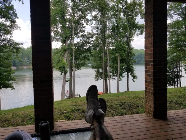 A view from a covered area overlooking a lake with trees and a dock. - Mayo Lake Lower Unit Highend, Clean, Updated (Roxboro)