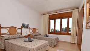 Una habitación de hotel con dos camas, una ventana con cortinas, un cabecero de madera y un cuadro en la pared.