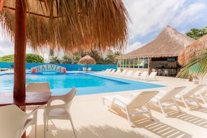 Relax by the SALVIA pool, surrounded by comfortable lounge chairs and a thatched-roof structure.