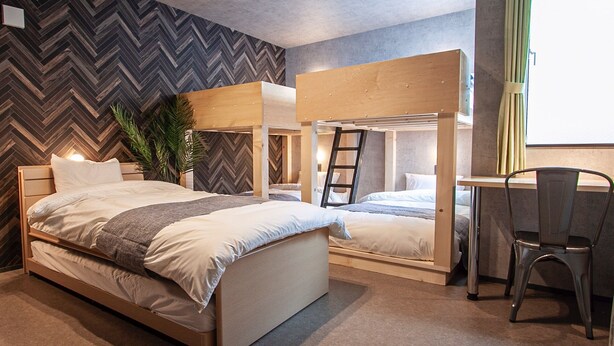 Een moderne slaapkamer met een wand in herringbone-motief, een stapelbed, een bureau en een stoel.