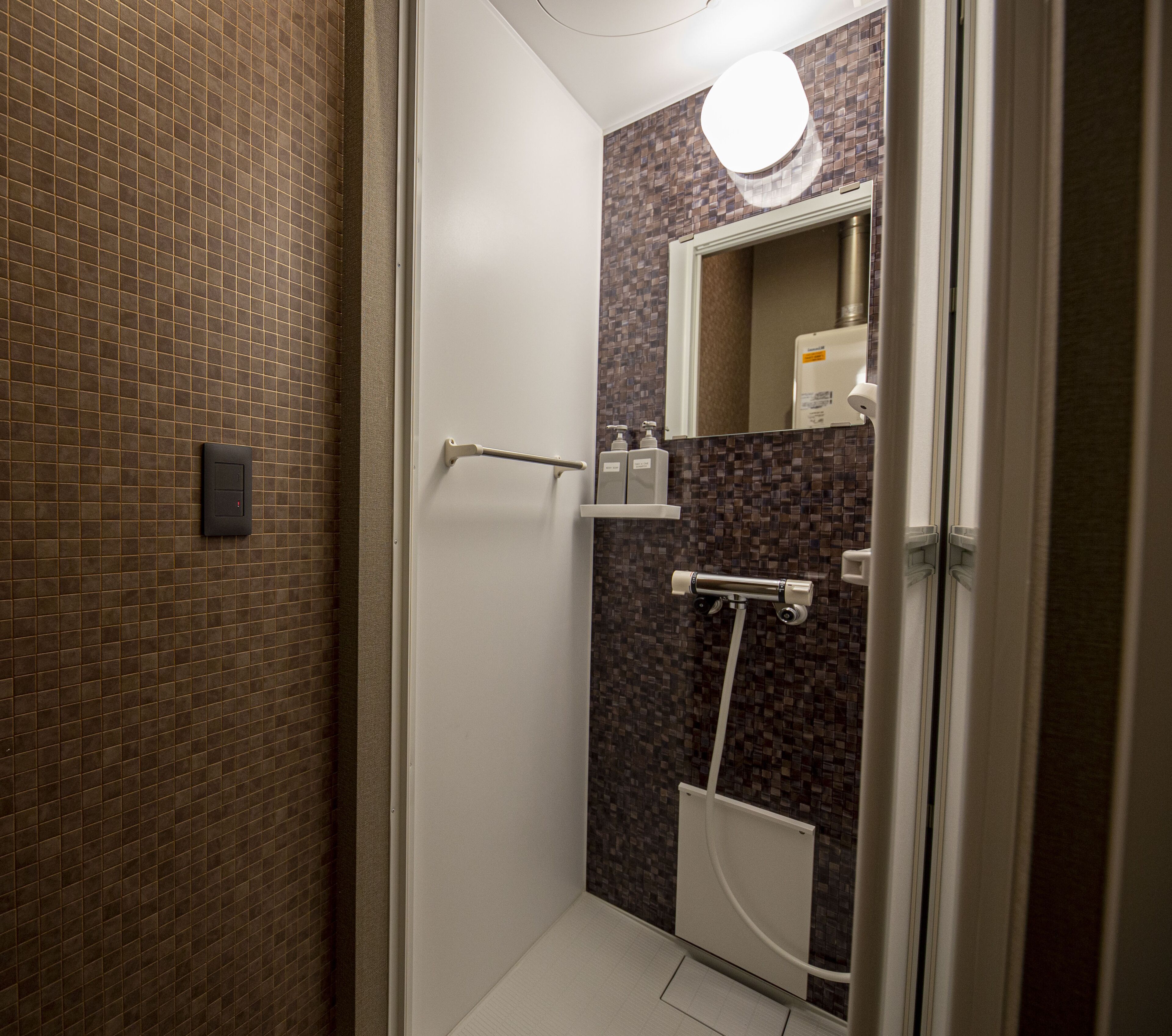 Et moderne badeværelse med bruser, toilet og håndvask. Der er et håndklædetørrestativ og et spejl over vasken.