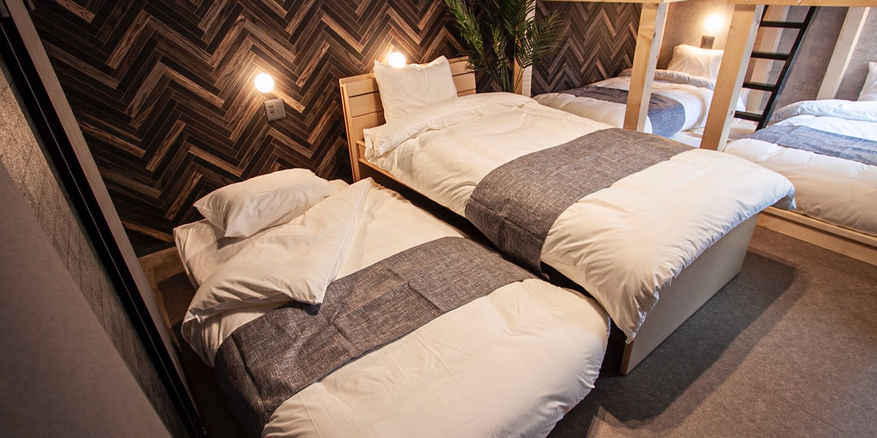 Ein Hotelzimmer mit zwei Betten, Holz-Kopfteilen und einer Wand mit Fischgrätmuster.