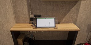 Een houten bureau met een tablet erop, aangesloten op een stekkerdoos.