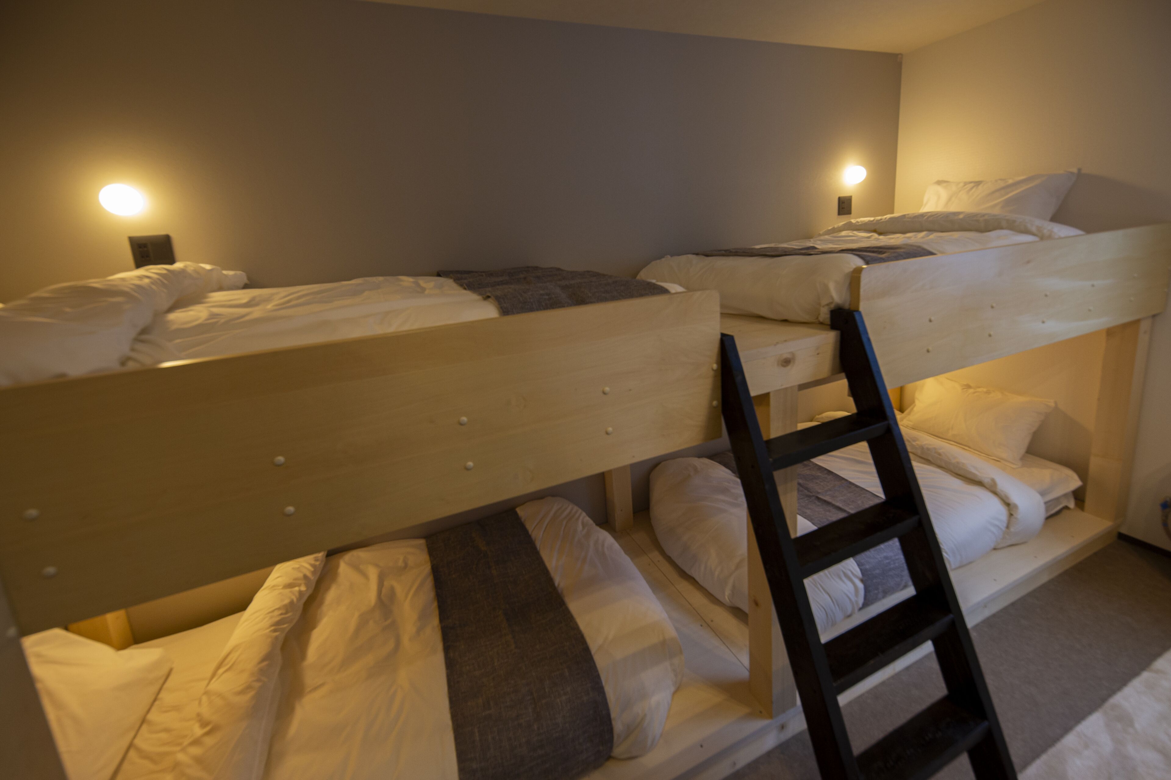 Une chambre avec un lit superposé et deux tables de chevet, chacune équipée d’une lampe. Une échelle est adossée au lit du bas.