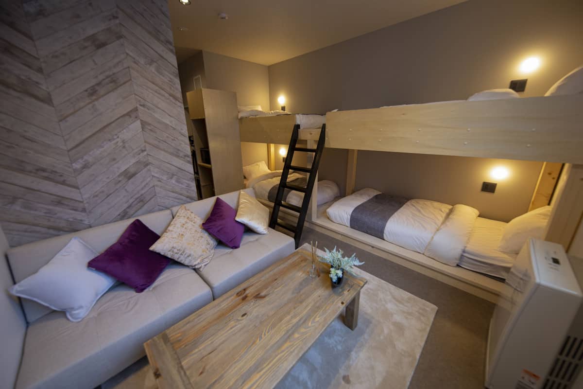 A bunk bed room with a sofa and a wooden coffee table.