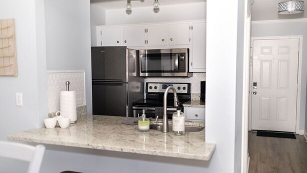 Una cocina moderna con armarios blancos, electrodomésticos de acero inoxidable y encimera de mármol.