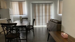 A compact living space with a dining area, a sofa, and a kitchen.