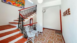 A staircase with red steps and white chairs, a colorful abstract painting, and a patterned floor. - Apartment Nina by Interhome (Marina di Caronia)