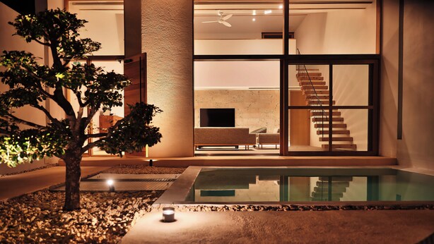 Una casa moderna con piscina, una escalera y un amplio ventanal con vista al interior.