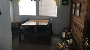 A dining area with a wooden table and blue upholstered chairs, a hanging light fixture, and a window with blinds. - Hidden Valley - Walk to Slopes and Pool - 2 BR with Fireplace + WIFI (Hidden Valley)