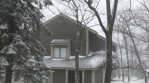 A two-story house with a small attic window, surrounded by snow-covered trees. - Hidden Valley - Walk to Slopes and Pool - 2 BR with Fireplace + WIFI (Hidden Valley)