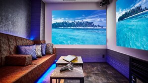 A modern room with a sofa, a table, and a large window with a tropical view. - Petit Bali Ikebukuro - Adults Only (Tokyo)