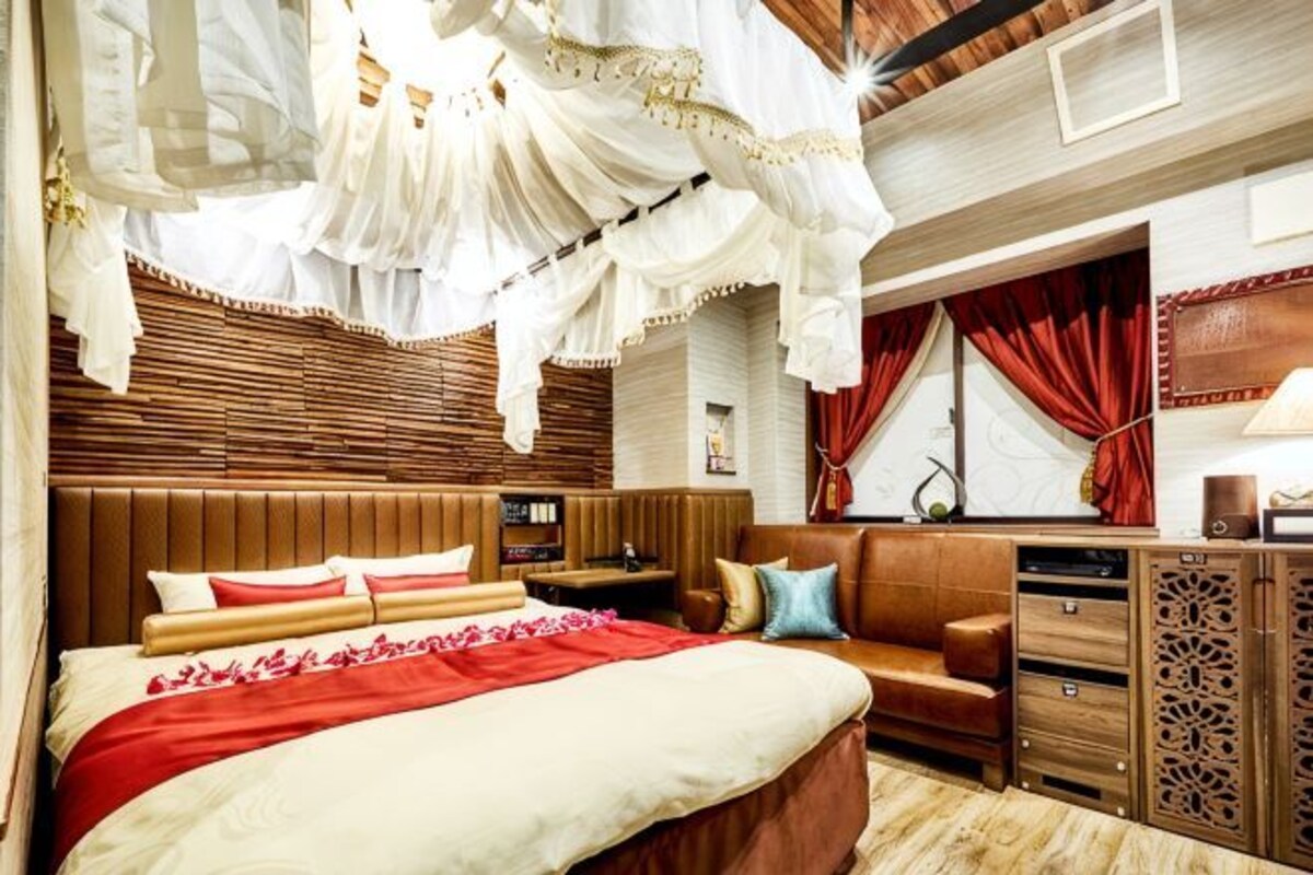 Une chambre à coucher avec un lit, des tables de chevet, une commode et une fenêtre avec des rideaux.