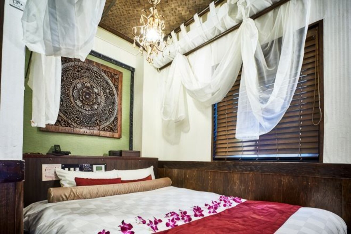 Une chambre à coucher avec un lit, une tapisserie murale et une fenêtre avec des rideaux.