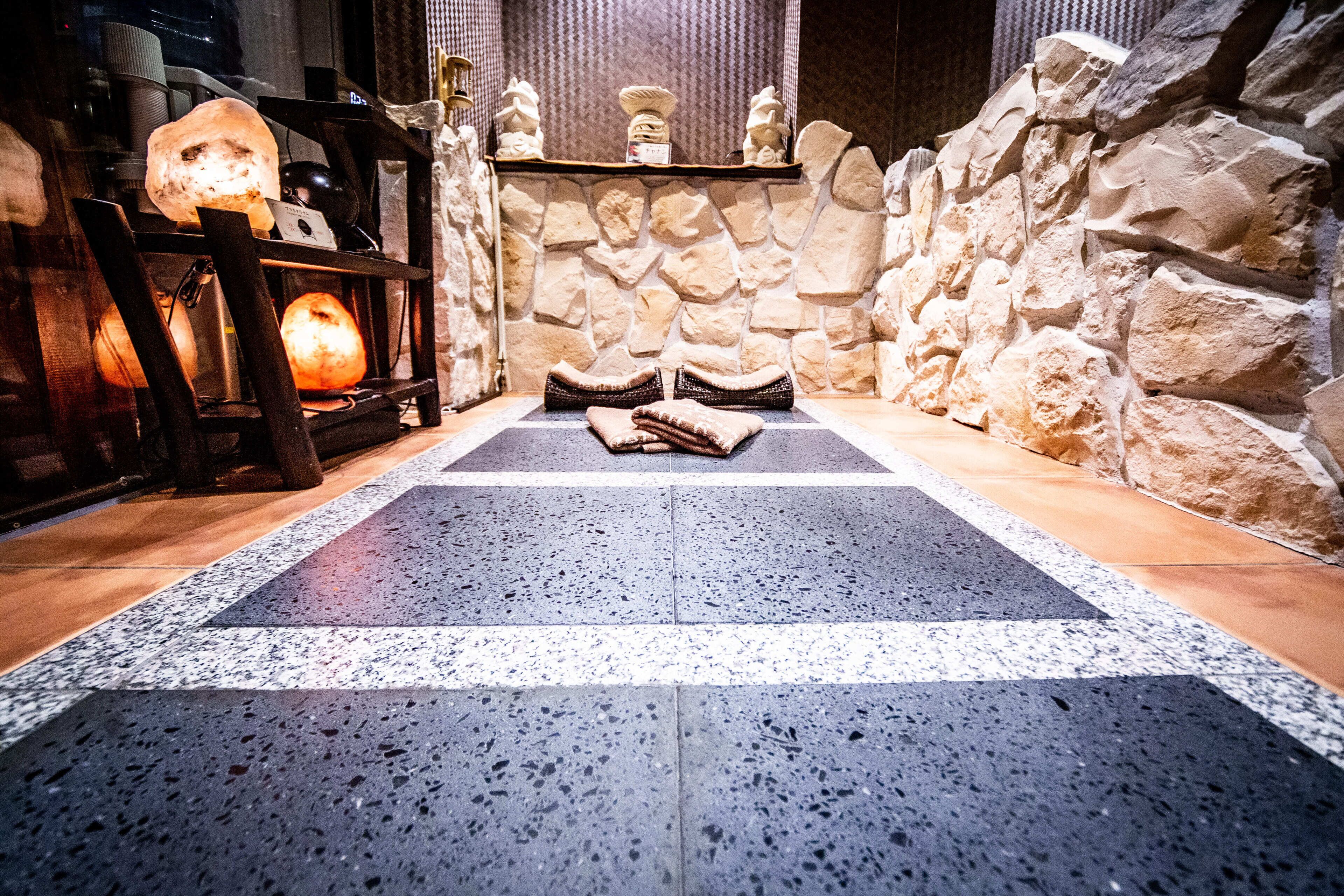 A spa area with a stone wall, a massage table, and a massage chair.