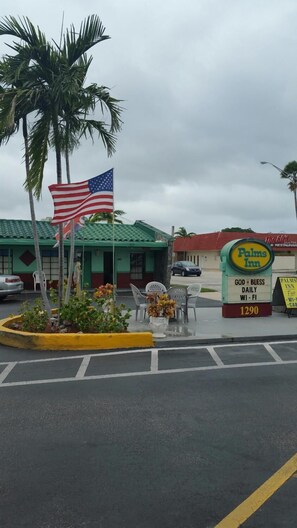 A parking lot with a sign for 'Palms Inn' and an American flag. - Palms Inn (Dania Beach)