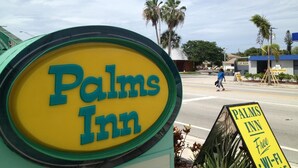 A sign for 'Palms Inn' with a clear view of the road and a car wash in the background. - Palms Inn (Dania Beach)