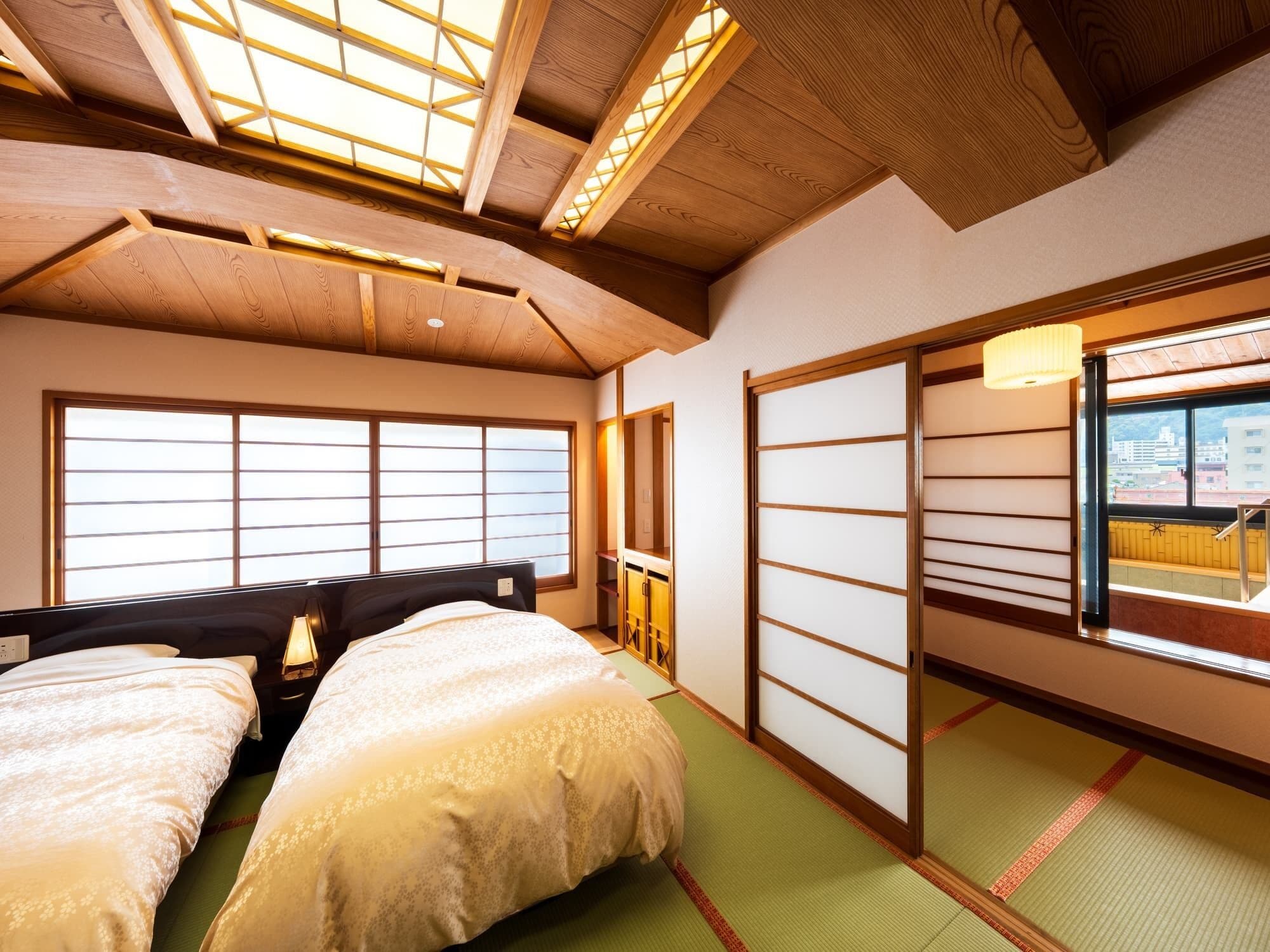 A traditional Japanese-style room with tatami flooring, a futon bed, sliding doors, and a skylight.