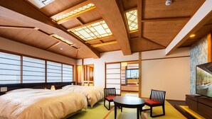 Perinteinen japanilaistyylinen huone, jossa on tatamimatto, sänky, pöytä tuoleineen ja televisio.
