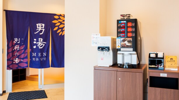 Et receptionsområde med kaffemaskine, vanddispenser og udstilling af kaffeposer.