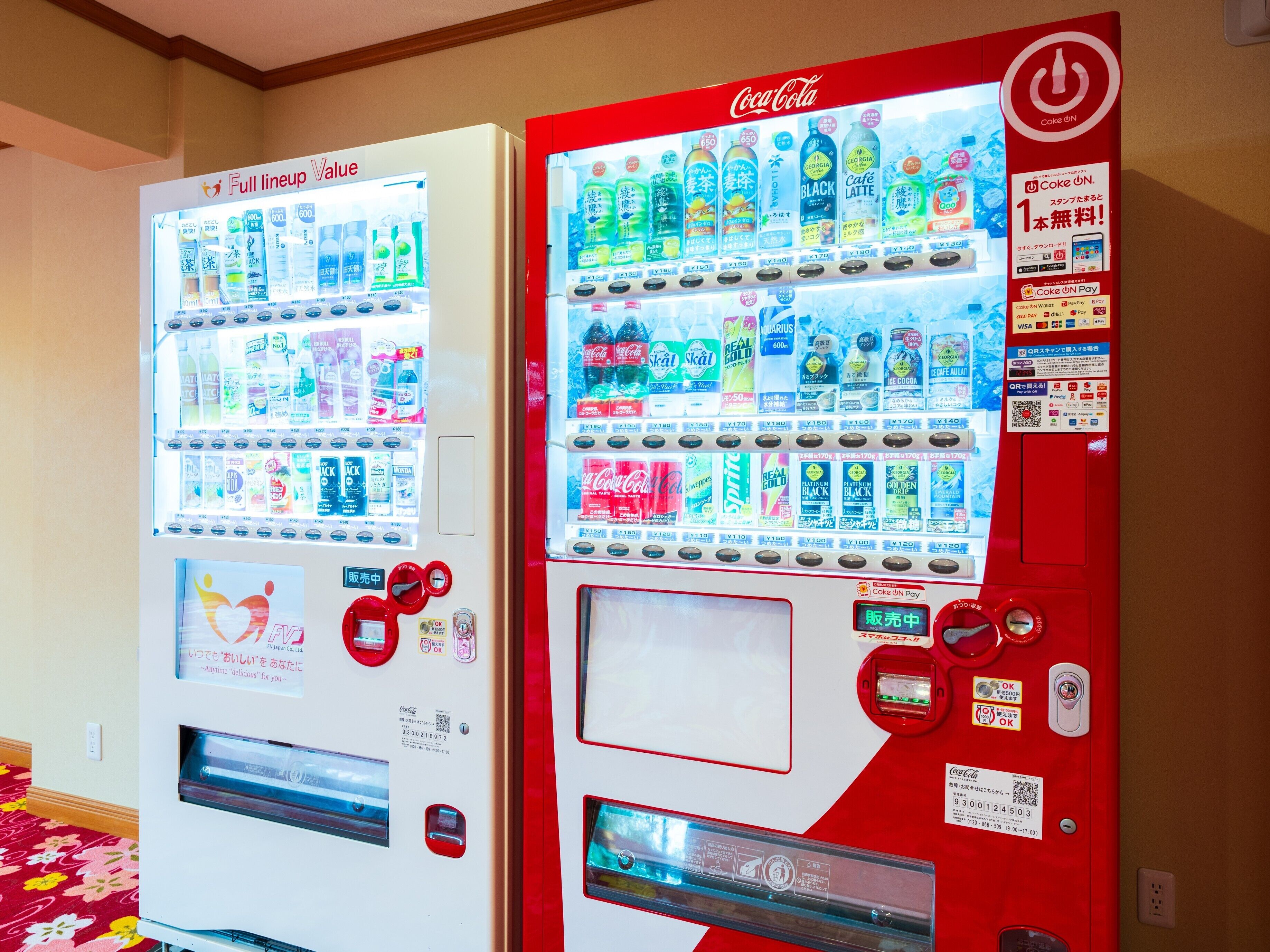 Two Coca-Cola vending machines with various beverage options and payment methods.
