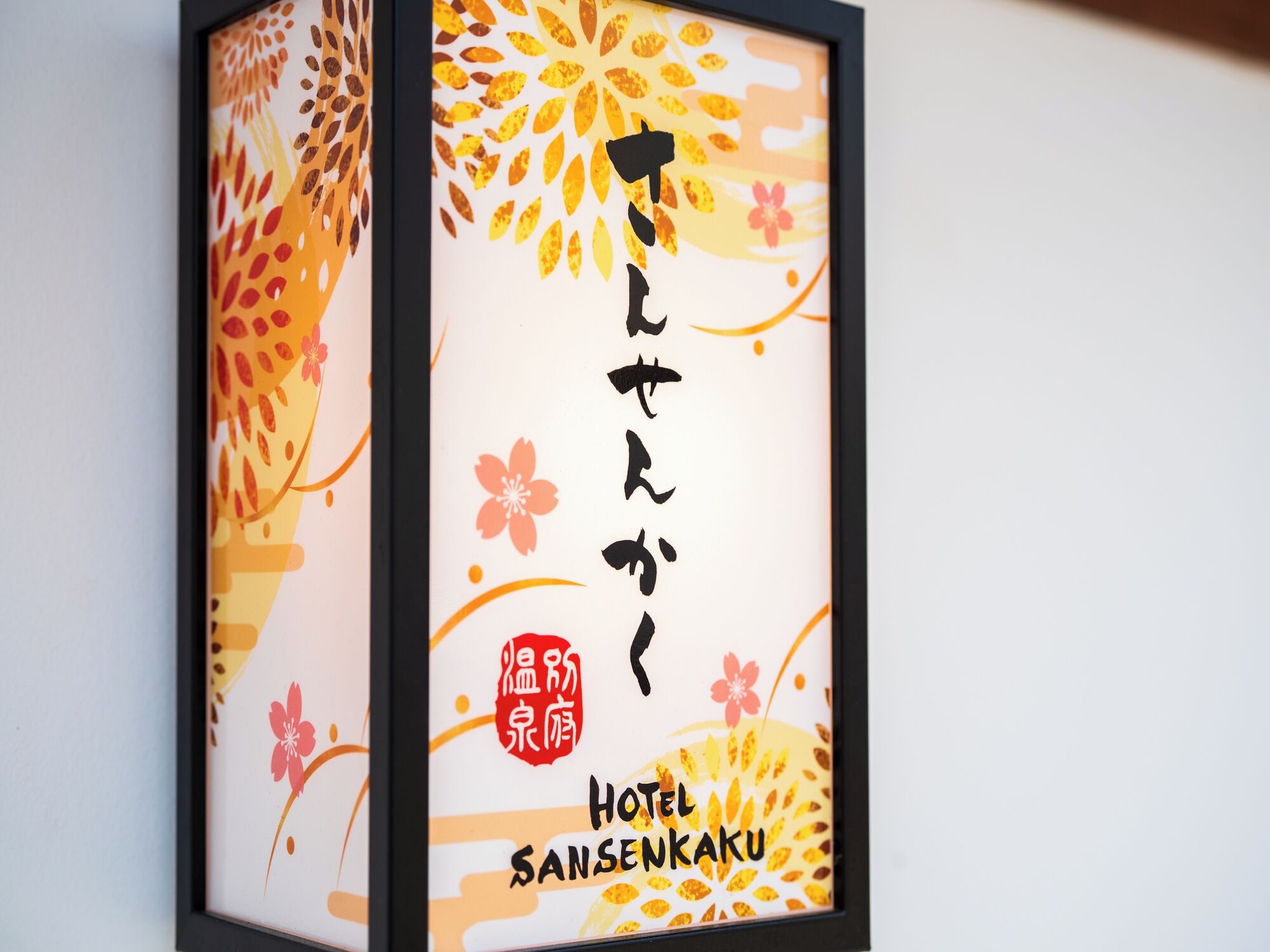 Un letrero enmarcado con caracteres japoneses y el nombre 'Hotel Sansenkaku'.