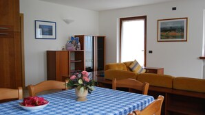 Un coin repas avec une table dressée pour deux personnes, un canapé et un meuble agrémenté d’un miroir.