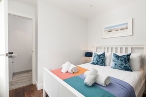 Ein Hotelzimmer mit Bett, einem Bild an der Wand und einer Tür zu einem Badezimmer.