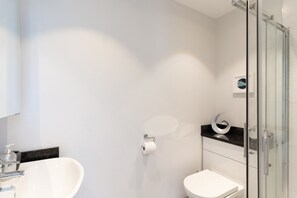 Ein modernes Badezimmer mit einer Duschkabine aus Glas, einem weißen Waschbecken und einer Toilette.