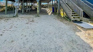 Une maison de plage dotée d’un porche couvert et d’un escalier menant à une terrasse.
