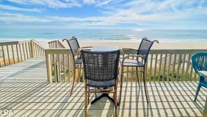 Une terrasse avec une table et des chaises donnant sur une plage.
