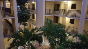 Un atrium d’hôtel à plusieurs étages, doté de balcons et de palmiers.