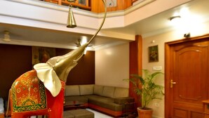 Um hall com uma grande estátua de elefante, um balcão de recepção de madeira, um sofá e um vaso de plantas.