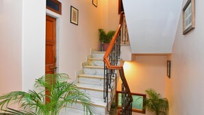 Uma escadaria com degraus de mármore, corrimãos de madeira e plantas em vasos.