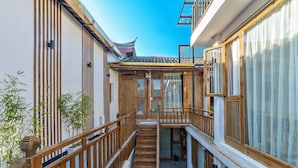 A traditional wooden building with a narrow corridor and a small garden area. - Easy Inn (Lijiang)