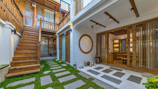 A multi-level wooden staircase leading to a balcony, a circular wooden feature, and a dining area with tables and chairs. - Easy Inn (Lijiang)