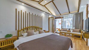 A modern bedroom with a wooden bed, a wooden bench, and a TV. - Easy Inn (Lijiang)
