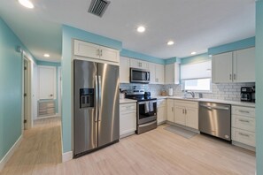 A modern kitchen with stainless steel appliances, white cabinets, and a light blue wall color. - Sea Spray 5: *Heated Pool *Steps to beach *Close to shops and dining (Anna Maria)