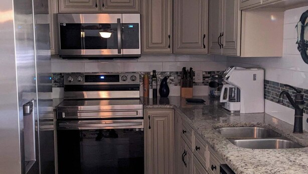 A modern kitchen with stainless steel appliances, light-colored cabinetry, and a granite countertop. -  AWESOME Location with a Canal view (Port Richey)