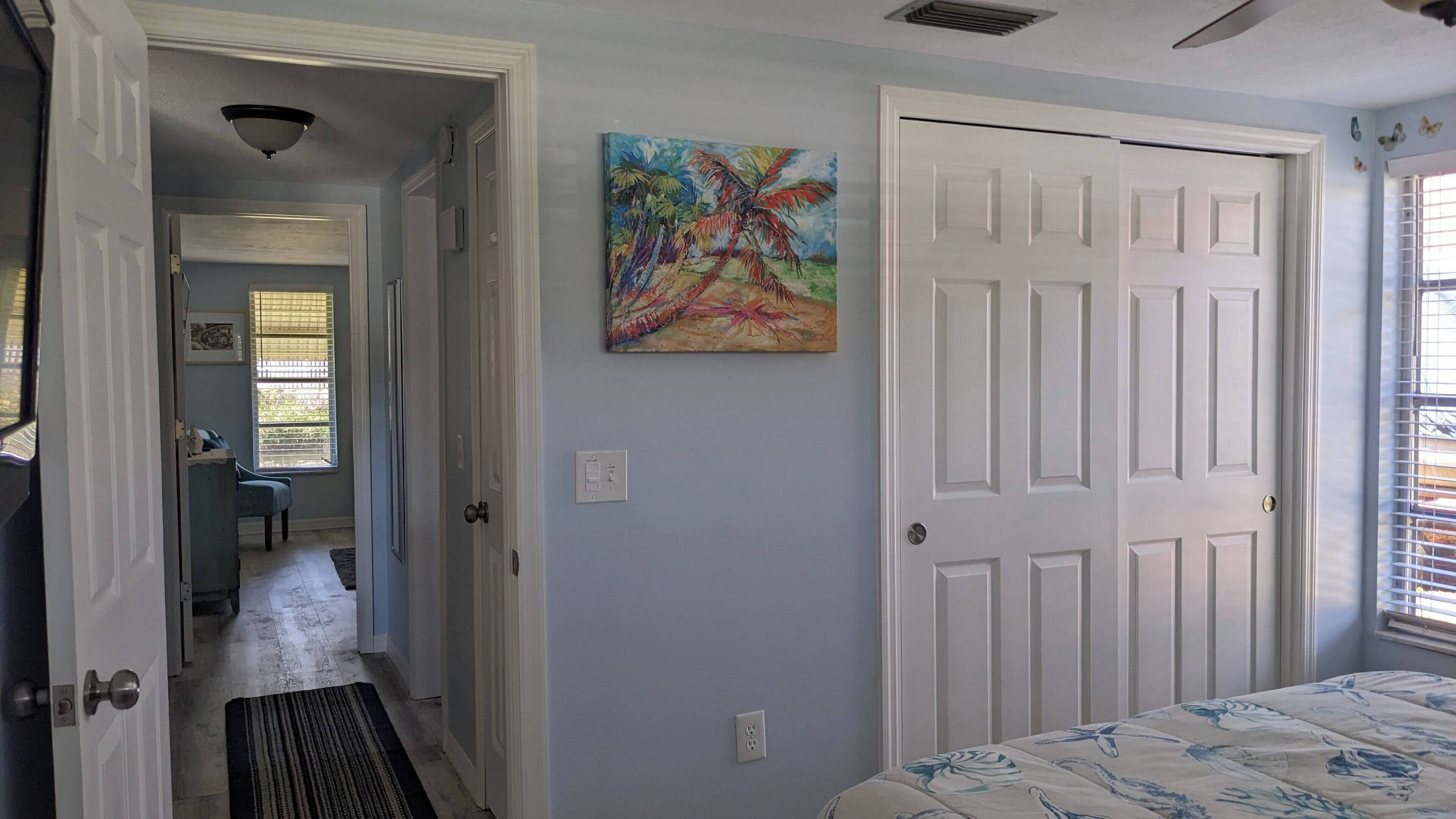 Une chambre à coucher avec un lit, une porte, un tableau et une fenêtre.