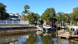 A calm water body with boats docked, a white picket fence, and a house with a blue exterior. -  AWESOME Location with a Canal view (Port Richey)