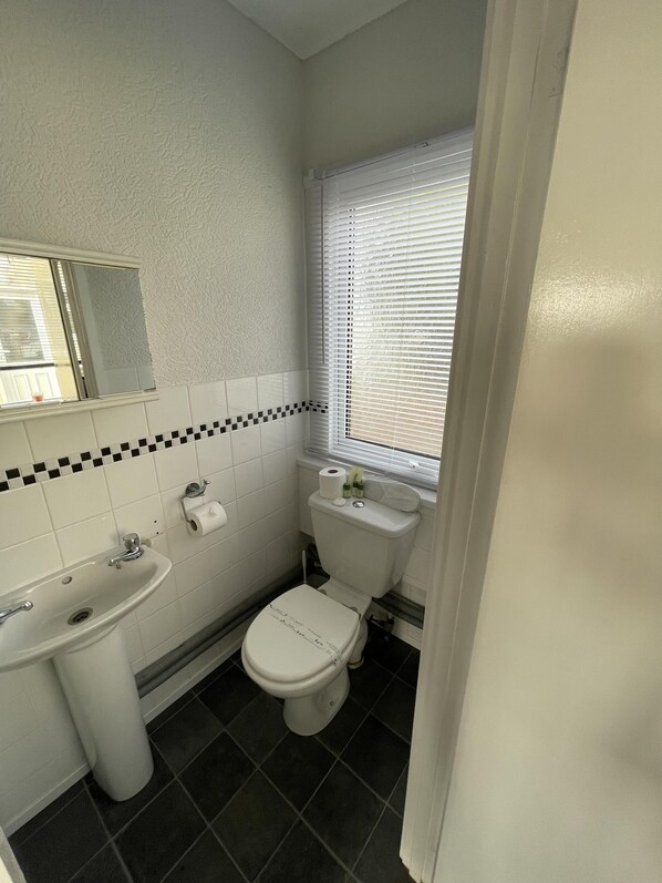 A small bathroom with a sink, toilet, and window. - Captivating 2-bed Chalet (Bridlington)