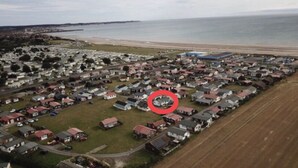 An aerial view of a residential area with houses, a beach, and a pier in the background. - Captivating 2-bed Chalet (Bridlington)