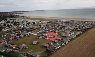 Vista aérea de una zona residencial con casas, una playa y un muelle al fondo.